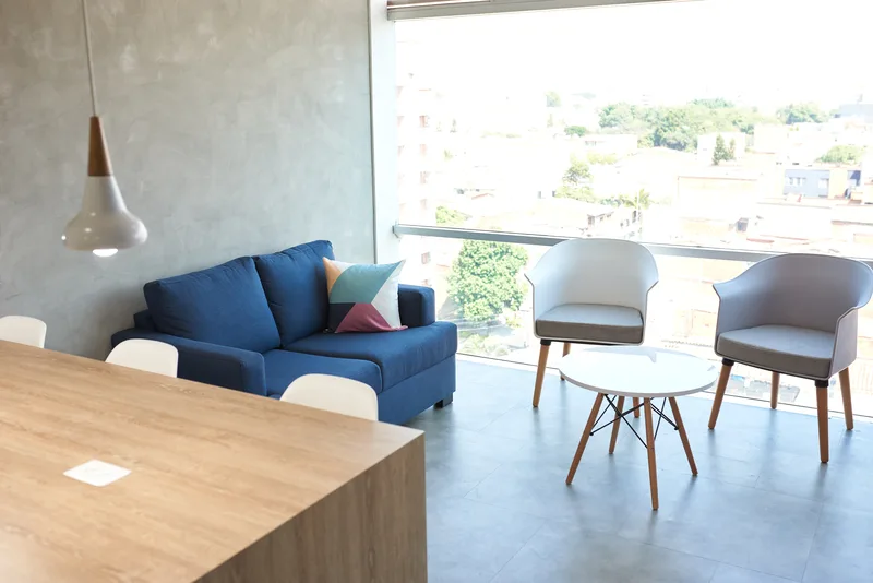 Sala de espera de Casa de Sonrisas — sofá azul junto a ventanal con vista a Laureles