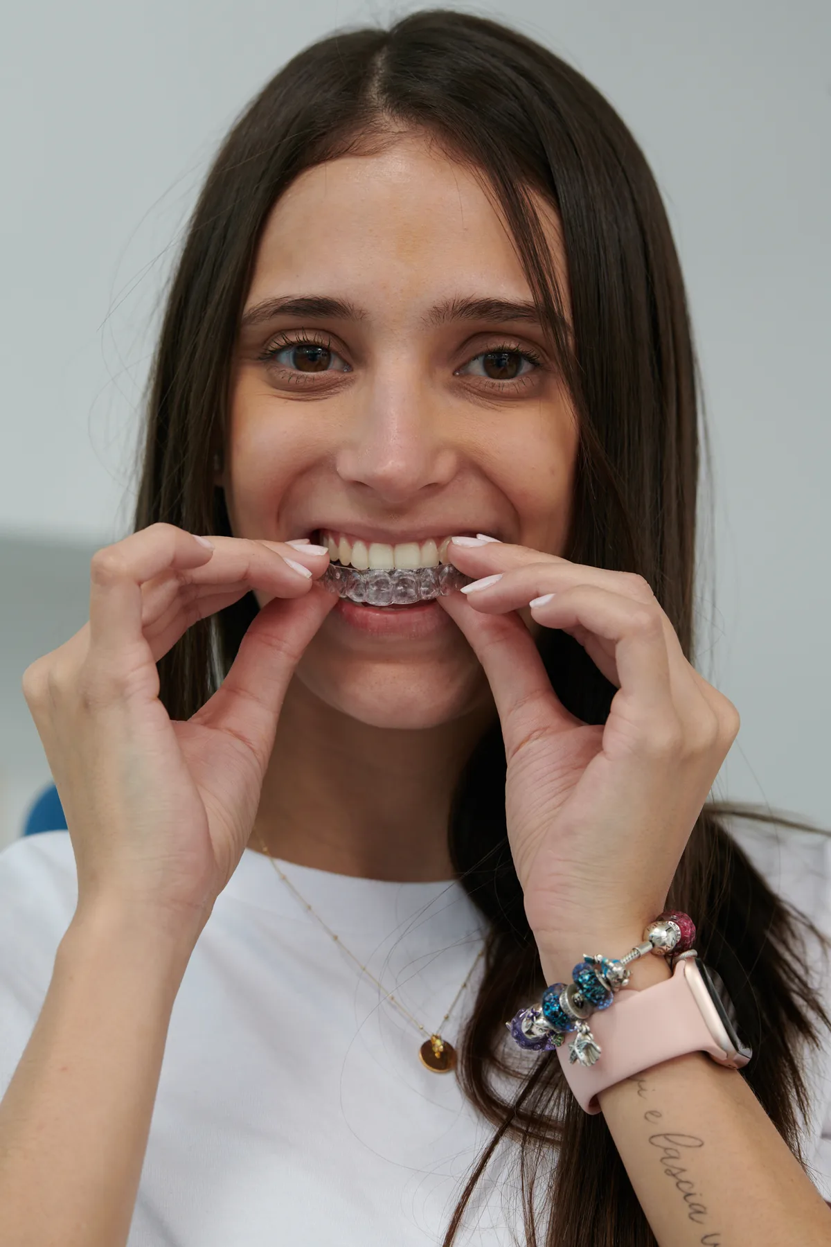 Paciente joven colocando alineador transparente en sus dientes
